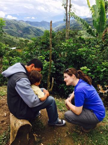 A Duke student kneels to talk to child in the mountain rainforest.
